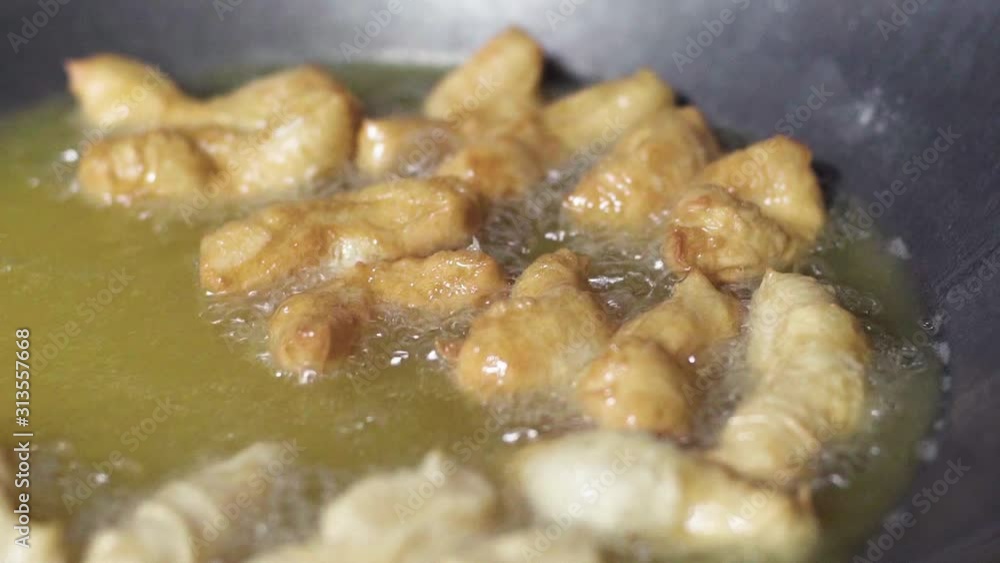 Frying deep fried dough sticks cooking hot oil in pan, Famous for eating in morning with hot soy bean milk Frying deep fried dough sticks cooking hot oil in pan, Famous for eating in morning with hot soy bean milk