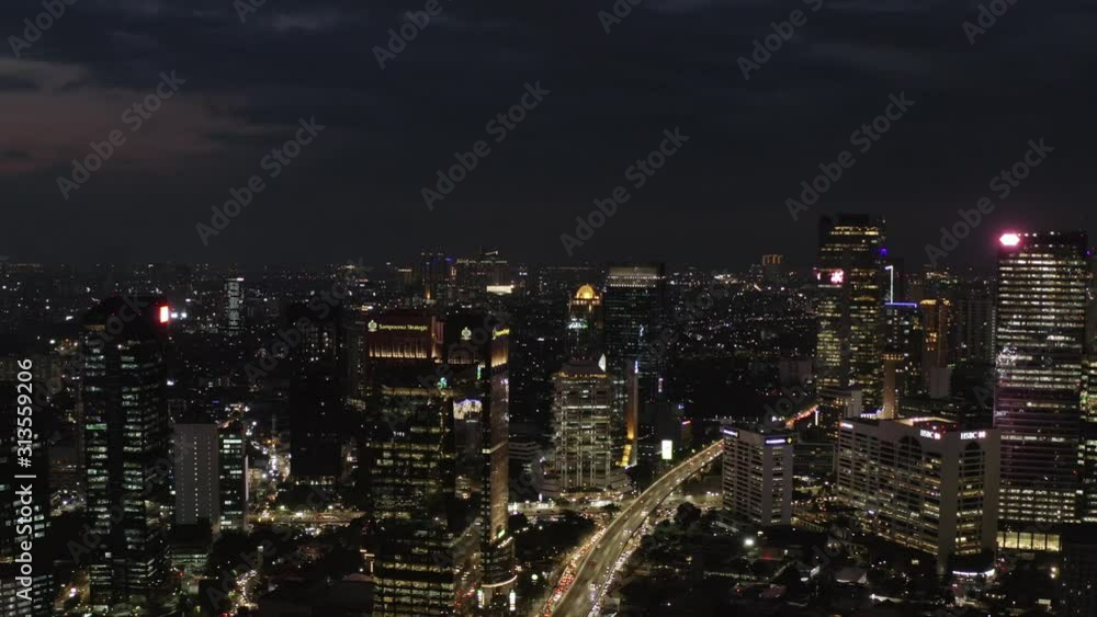 night aerial view of Jakarta city after sunset, tall buildings with busy highway with cars passing by. Dolly motion night aerial view of Jakarta city after sunset, tall buildings with busy highway with cars passing by. Dolly motion