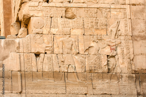 Karnak temple complex in Luxor, Egypt. Ancient bas relief with hieroglyphs on wall, pharaoh and god.