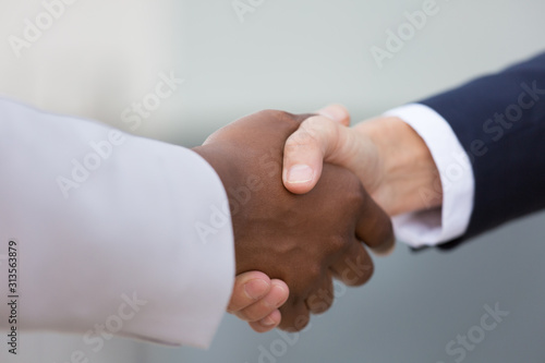 Closeup of multiethnic female business handshake. Business women shaking hands outside. Greeting or communication concept