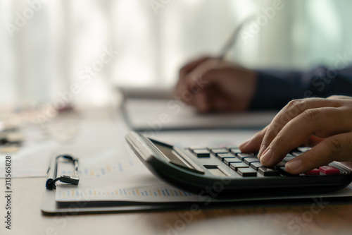 Businessman working on desk office with Investors are calculating on calculator investment costs.