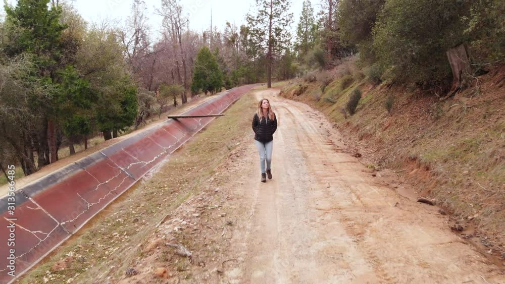 Pull Back of Woman Walking Through Forest Down Dirt Road Toward Camera Pull Back of Woman Walking Through Forest Down Dirt Road Toward Camera