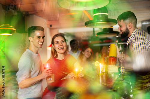 Young man bartender shaking cocktail for friends during patry