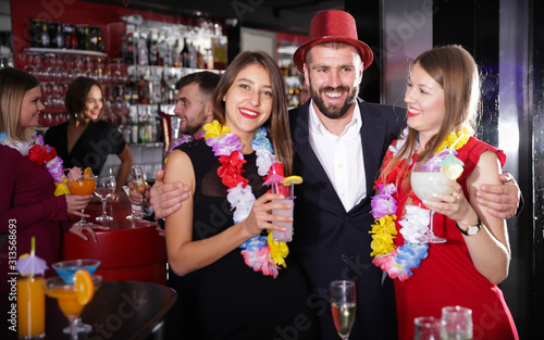 Guy with two girls on Hawaiian party in bar
