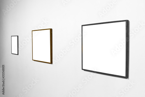 Three empty blank picture wooden frames in interior on white wall