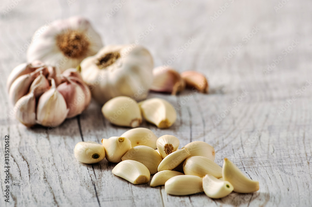 Garlic Cloves and Bulb in wooden bowl on white table. Garlic Cloves and Bulb in wooden bowl on white table.