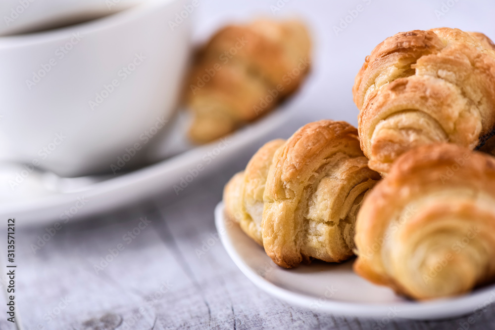 Cup of coffee on wooden tray with croissants.