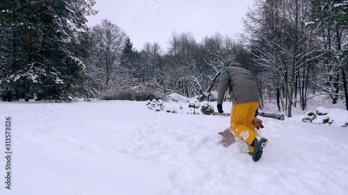 The man and his dog, the red-haired cocker spaniel, frolic in the snow. Outdoor activities in the winter during a snowfall, a man and a companion dog play together, slow motion stock video