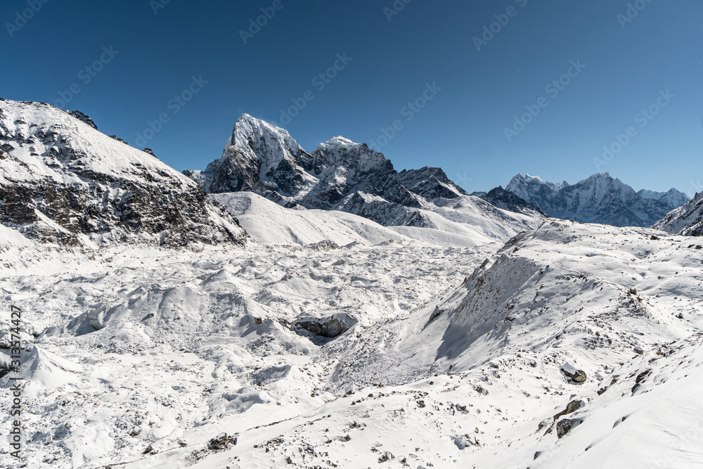 Ngozumpa glacier with the Cholatse peak in the background during a winter day in  from Gokyo in the Himalaya in Nepal