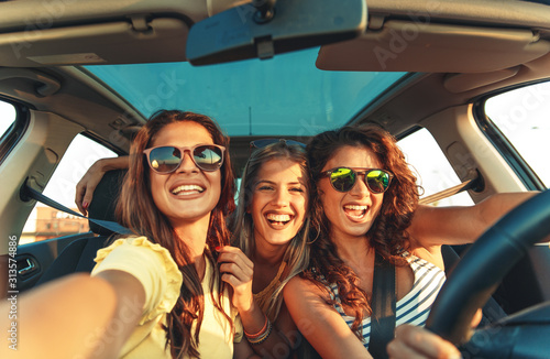 Three female friends enjoying traveling at vacation in the car. © Zoran Zeremski