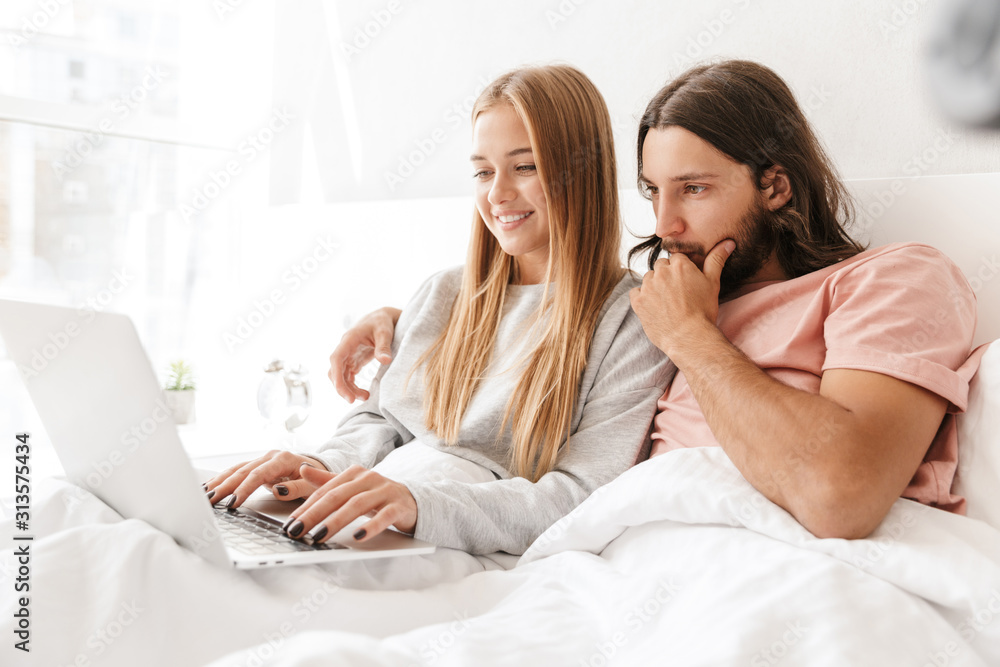 Loving couple in bed using laptop computer at home. Loving couple in bed using laptop computer at home.