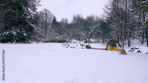 The man and his dog, the red-haired cocker spaniel, frolic in the snow. Outdoor activities in the winter during a snowfall, a man and a companion dog play together, slow motion stock video