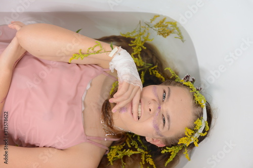 a girl in a white dress is lying in a bath with milk and flowers