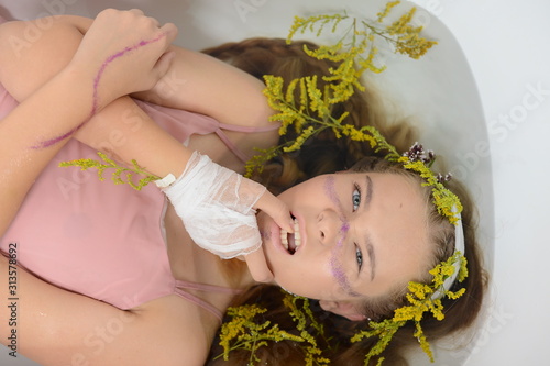 a girl in a white dress is lying in a bath with milk and flowers