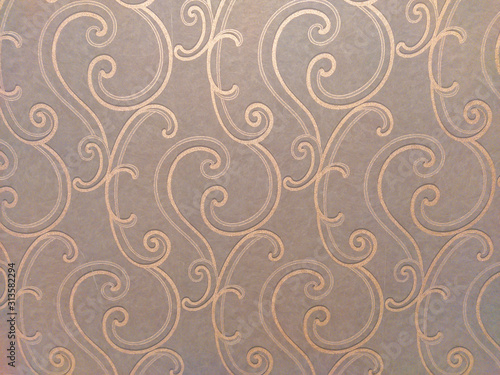 Luxurious and oriental looking decoration on the wallpaper in brown color with golden ornaments in swirls and curves shape