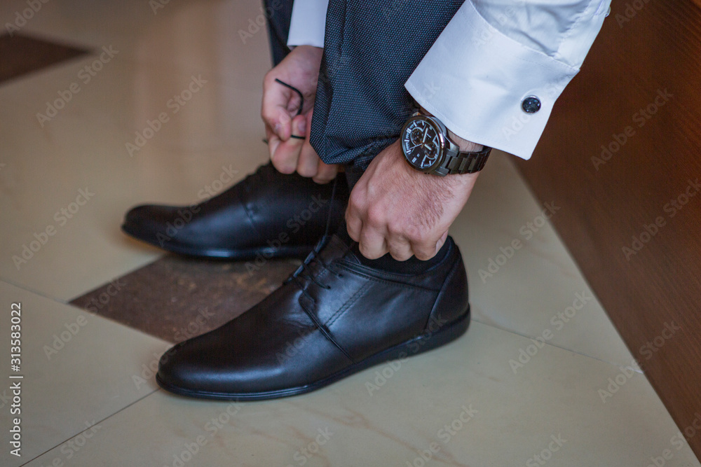 groom's dress and wedding preparation. helping the groom get dressed, put on his watch, shoes, tie, bow tie and jacket.