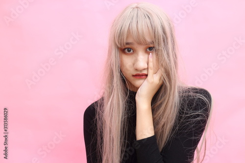 Beautiful girl makes herself the makeup, isolated Beautiful Asian models over  pink  background for advertising concept