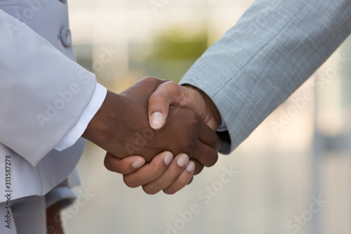 Multiethnic male and female leaders greeting each other in city. Closeup of business man and woman shaking hands outside. Cooperation concept