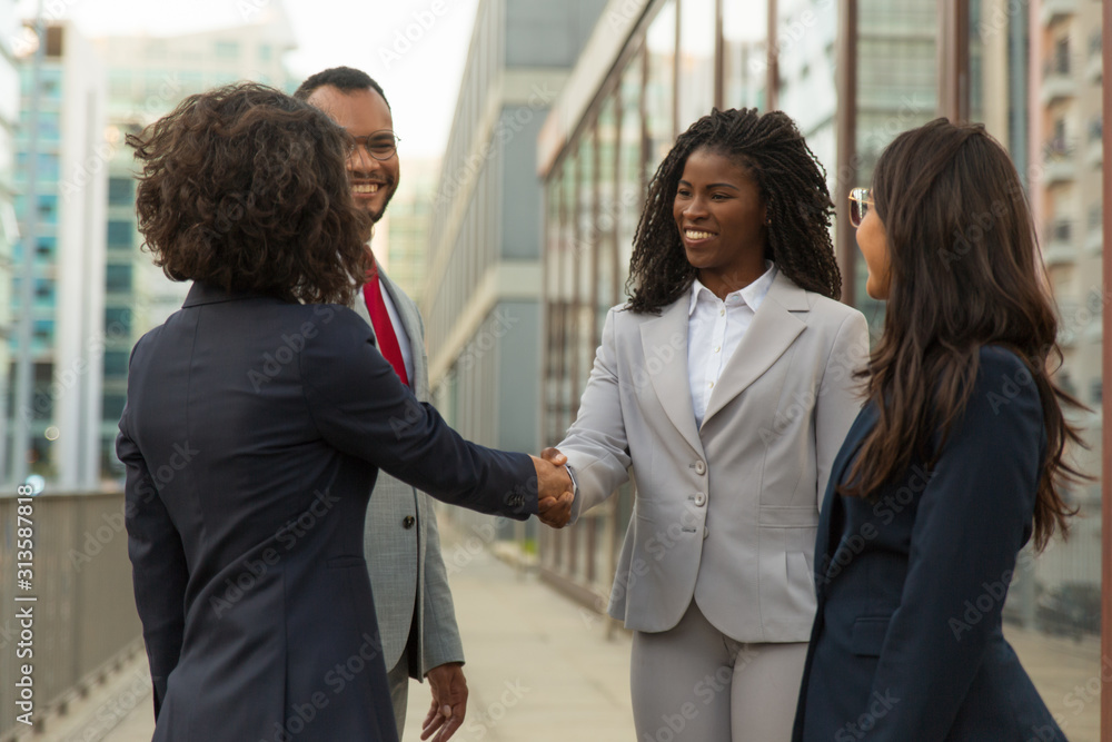 Successful company representatives greeting each other near office building. Business man and women shaking hands with each other outside in city. Dealing concept