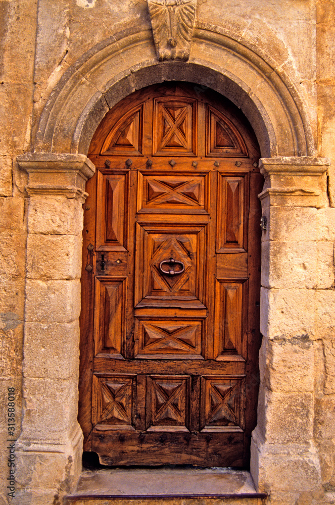 An old decorated wooden door with surrounding stonework in Provence South of France