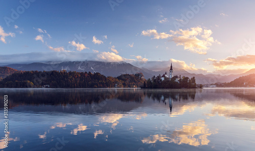 Wonderful morning landscape with calm lake and colorful sky under sunlight in Slovenia. Sunset over Lake Bled with Bled Castle and Mountains in the background. Popular Travel destination.