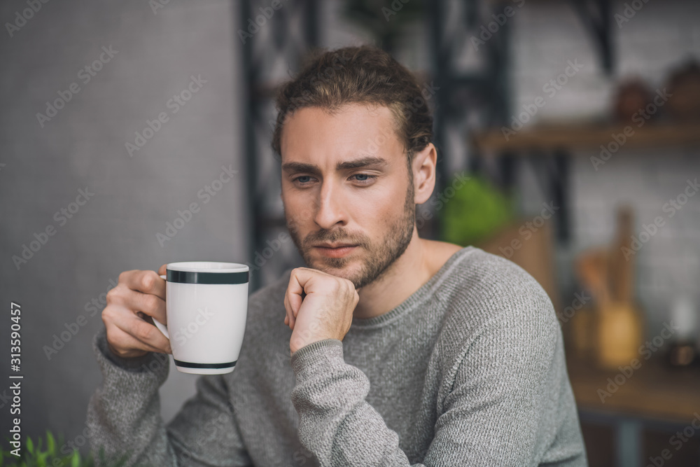 Young bearded handsome man in grey looking disturbed Young bearded handsome man in grey looking disturbed