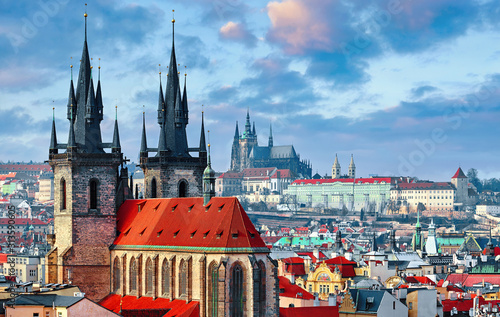 High spires towers of Tyn church in Prague city (Church of Our Lady before Tyn cathedral) urban landscape panorama with red roofs of houses in old town and blue sky with clouds.