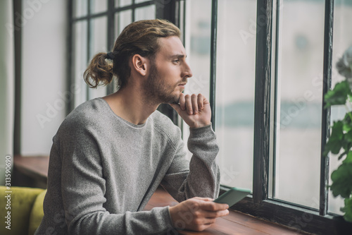 Young bearded handsome man in grey feeling thoughtful photo