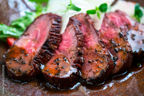 Foto Cooked fillet of beef tenderloin sliced on a plate with an Italian salad
