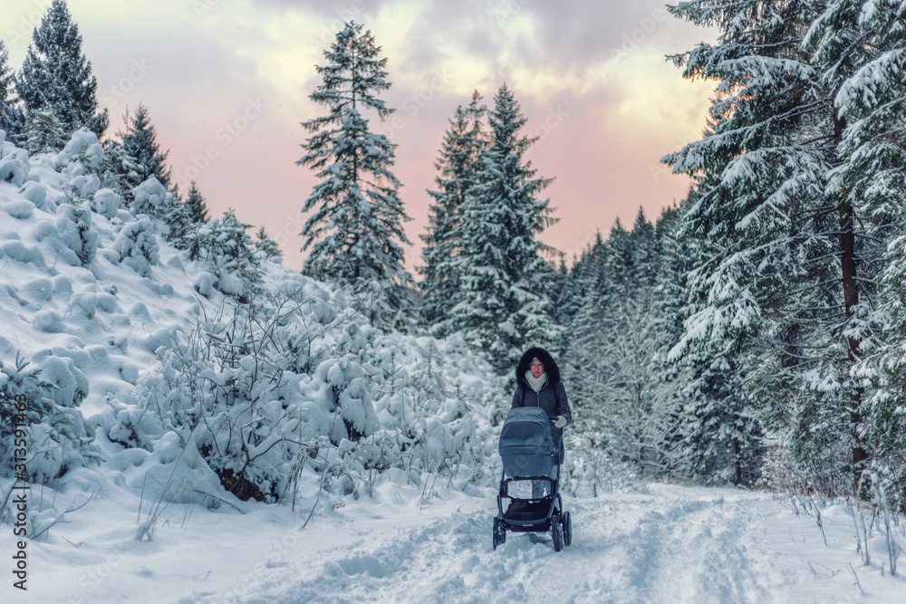 Mother with pram in snowy winter forest