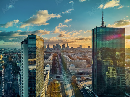 Beautiful panoramic aerial drone view to the Сenter of modern Warsaw city with silhouettes of skyscrapers in in the rays of the setting winter January sun - amazing sunset, Poland