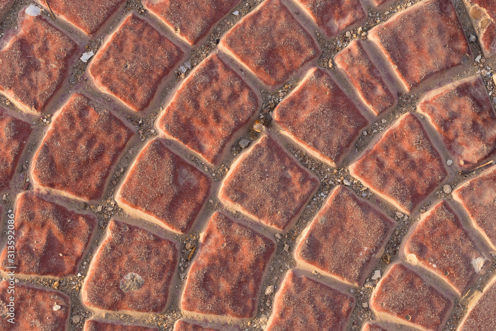 Fototapeta premium Sidewalk tiles with a pattern. A concrete slab painted red. Decorative element for decoration of the exterior.