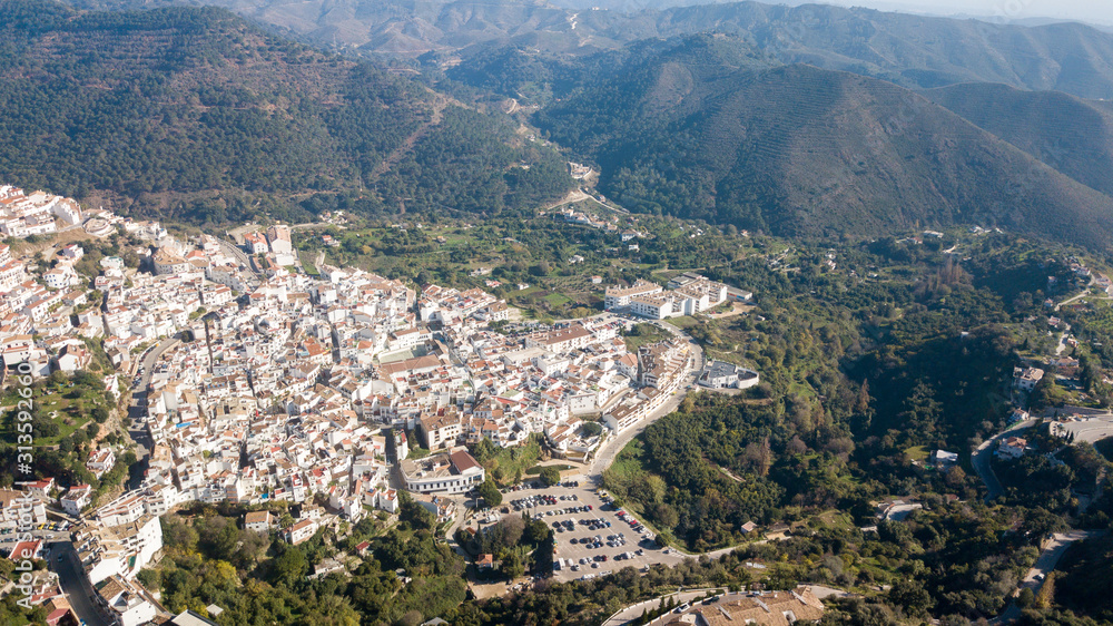 aerial photograph of a town in the south of spain next to marbella, between mountains and green vegetation