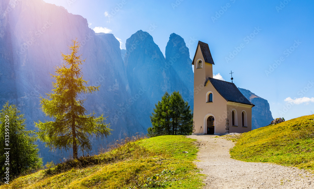 Chapel of San Maurizio at Passo Gardena, South Tyrol, Italy.  View to path to small white chapel San Maurizio and Dolomiti mountain. San Maurizio chapel on the Gardena Pass, South Tyrol, Italy.