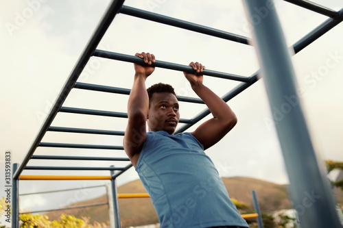 African American man exercising on horizontal bars © StratfordProductions