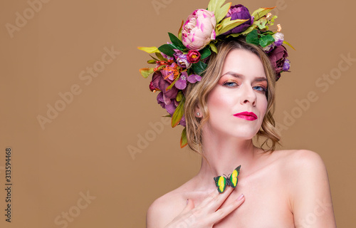 tender young woman posing in flower wreath with artificial  greenbutterfly,  isolated on ochet background. Bow tie concept. Beautiful lady with her green butterfly on the neck photo