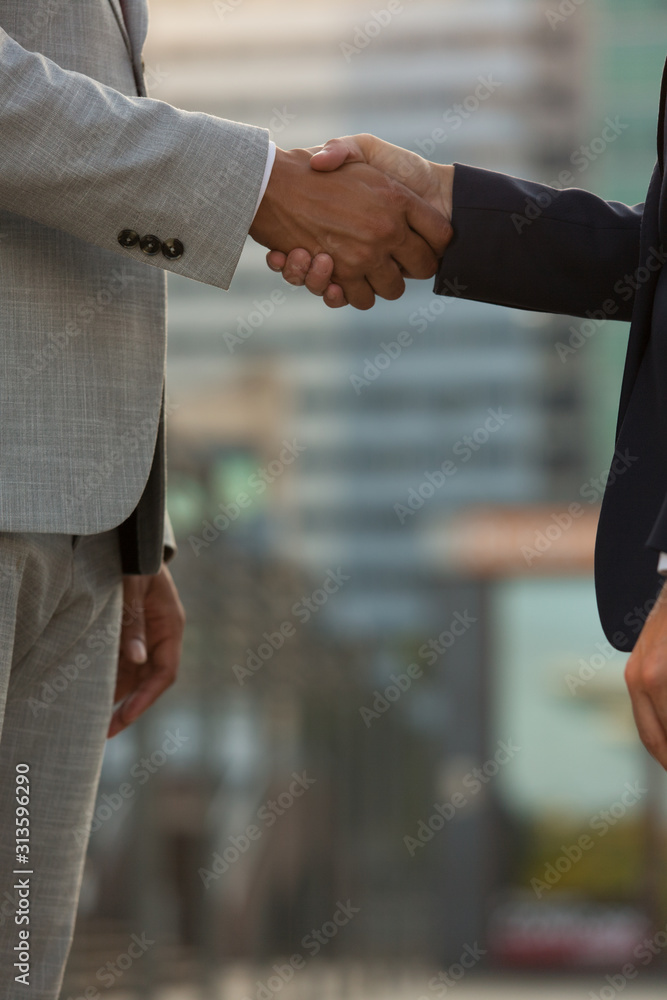 Businesspeople wearing formal suits greeting each other in city. Closeup of business man and woman shaking hands outside. Partnership concept