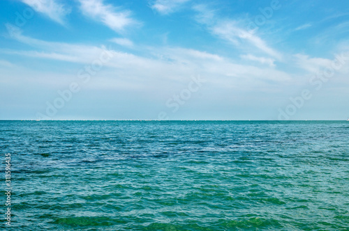 Calm sea in summer bright sunny day sailboats away on the horizon