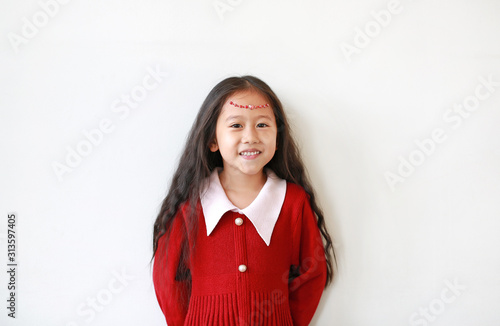 Portrait of pretty little girl in red dress with Crystals on forehead and smiling over white background. © zilvergolf