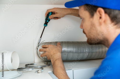 Fotografie worker installing flexible aluminum ventilation tube for kitchen cooker hood exh