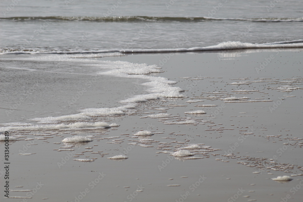 Paysage invitant à la relaxation et au vien-être : plage avec mousse et écume blanche sur le sable en Vendée, France