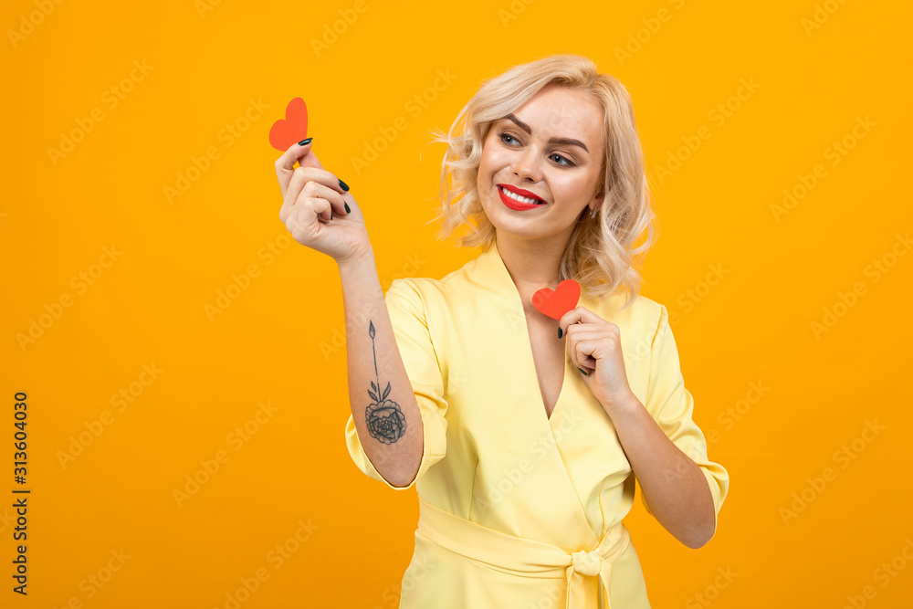 valentine's day concept. blond girl holds small valentines cards in the form of hearts on a yellow background valentine's day concept. blond girl holds small valentines cards in the form of hearts on a yellow background