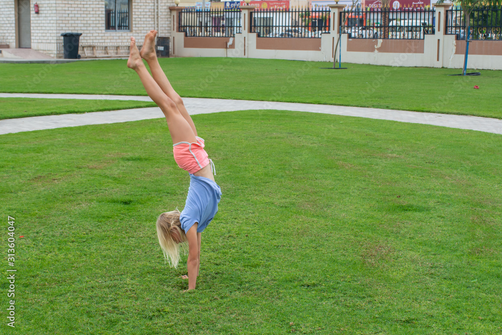 Young girl does a handstand, cartwheel or round off upside down showing fitness, flexibility and agility.
