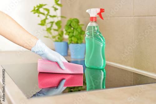Woman in gloves cleaning kitchen.