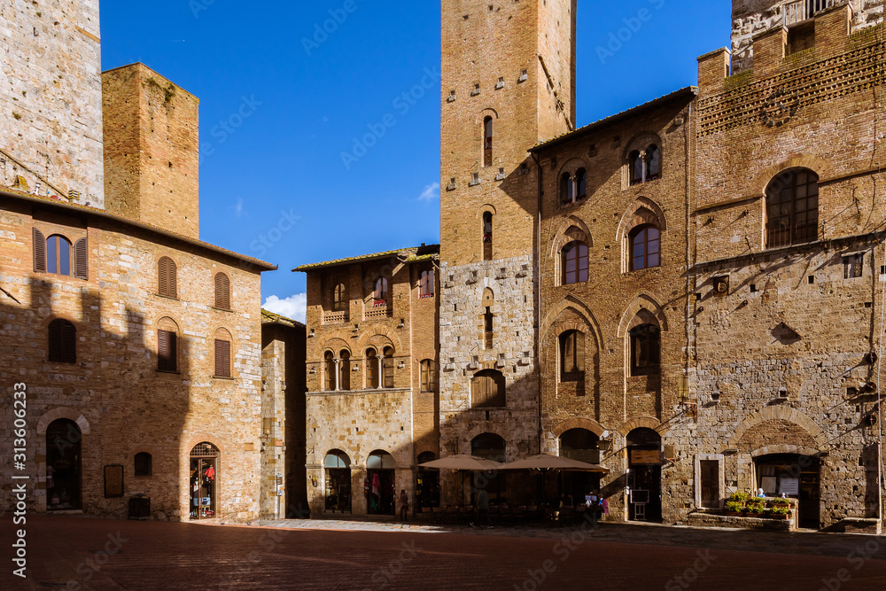 Medieval architecture with brick buildings in a small town in Tuscany, Italy under the blue sky. Light and shadow.