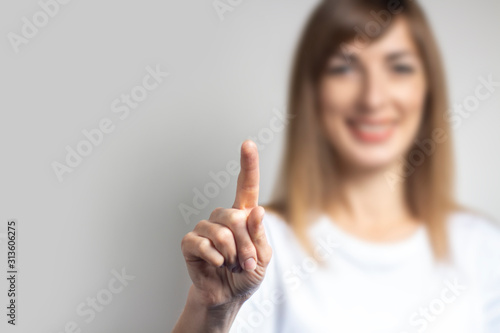 Young woman touches or pushes a finger at something on a light background photo