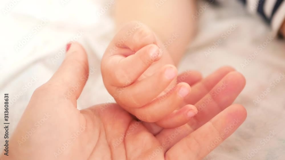 Mom strokes the hand of a newborn baby. Close-up of mom holding his baby fingers. mother strokes the finger of her newborn baby. the mother gently strokes the tiny little arms of her newborn baby. Chi Mom strokes the hand of a newborn baby. Close-up of mom holding his baby fingers. mother strokes the finger of her newborn baby. the mother gently strokes the tiny little arms of her newborn baby. Chi