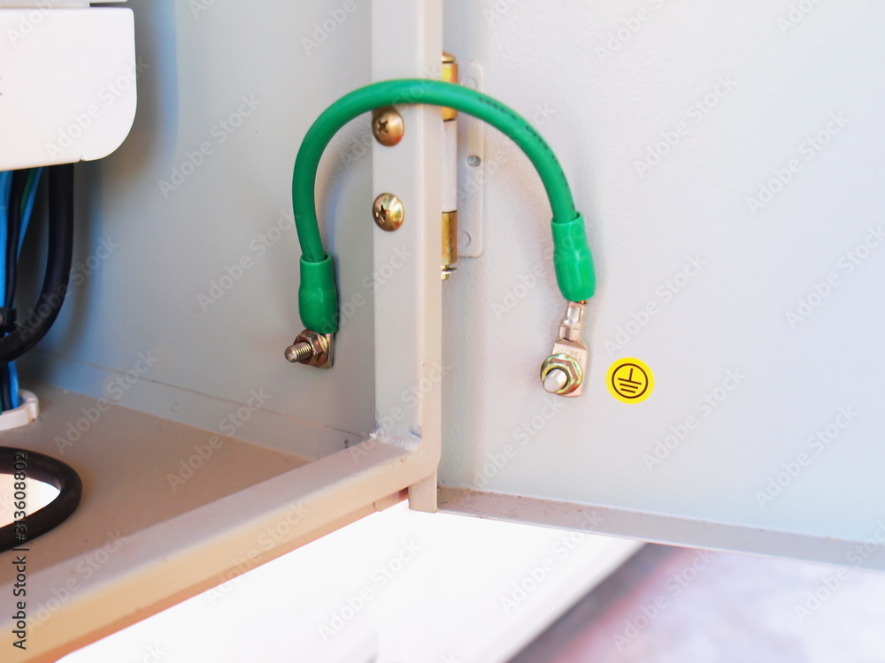 Foto de Closeup of green ground wire in a metal box The gray breaker