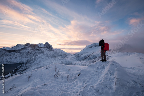Photographer taking a photo on top of snowy mountain in the morning at Senja island © Mumemories