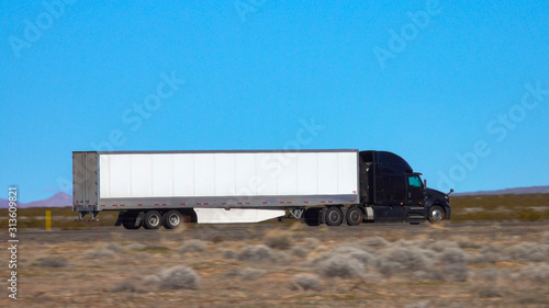 CLOSE UP: Black truck speeds along the interstate highway crossing a desert